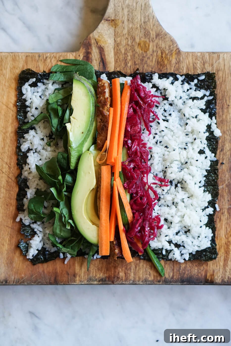 A piece of nori is topped with sushi rice and vegetables.