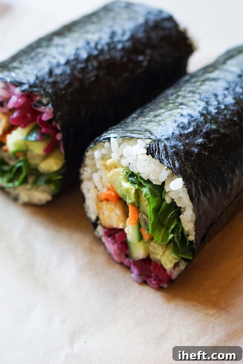 A close up photo of a vegan sushi burrito filled with spinach, avocado, cucumber, carrots and tempeh.