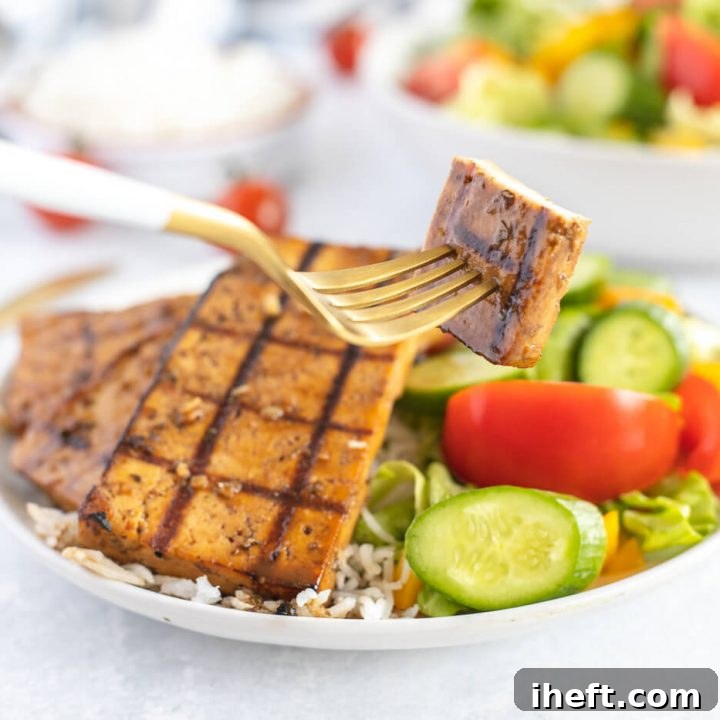 A bowl of veggies and rice topped with grilled tofu.