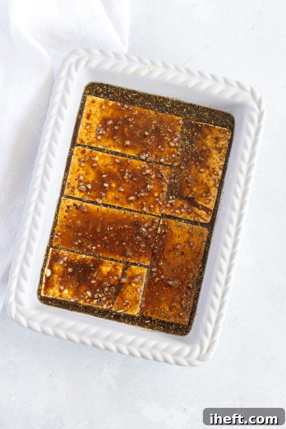 Sliced tofu marinates in a white dish.