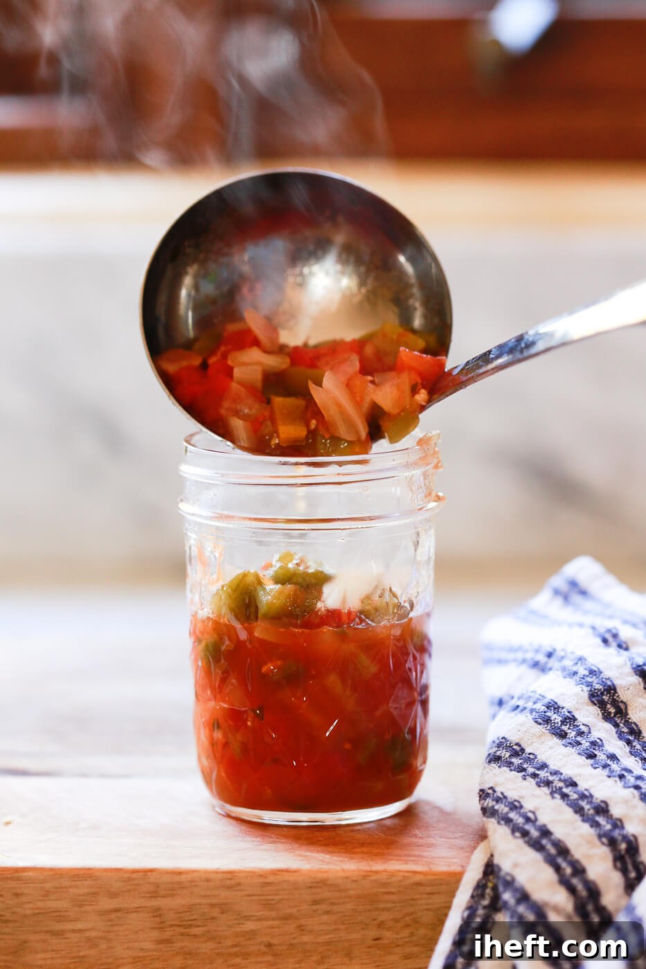 Hot canning salsa is ladled into a warm Ball canning jar.