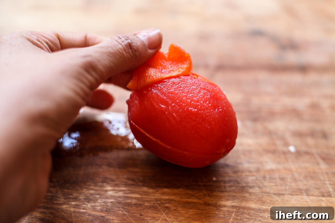 The skin of a Roma tomato is peeled off after blanching.