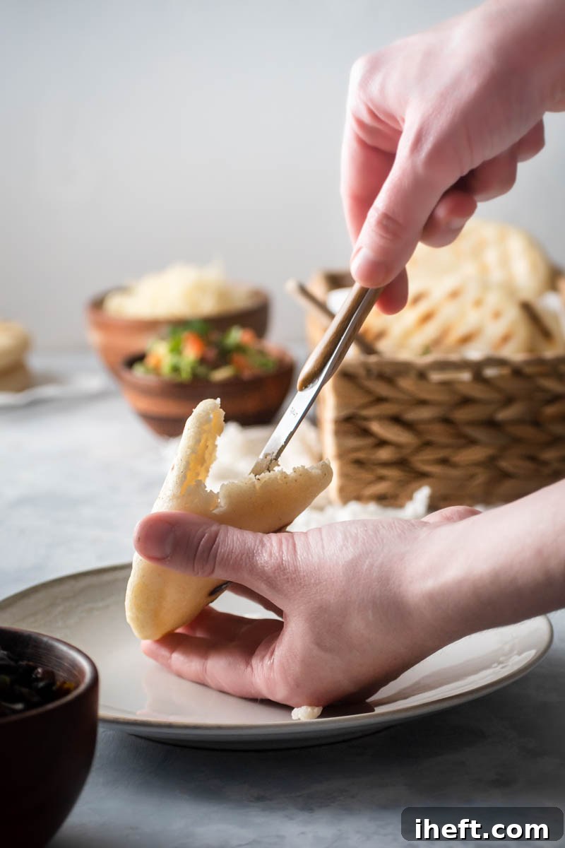 A freshly grilled arepa, perfectly golden and slightly puffed, waiting to be split open and filled with delicious ingredients.
