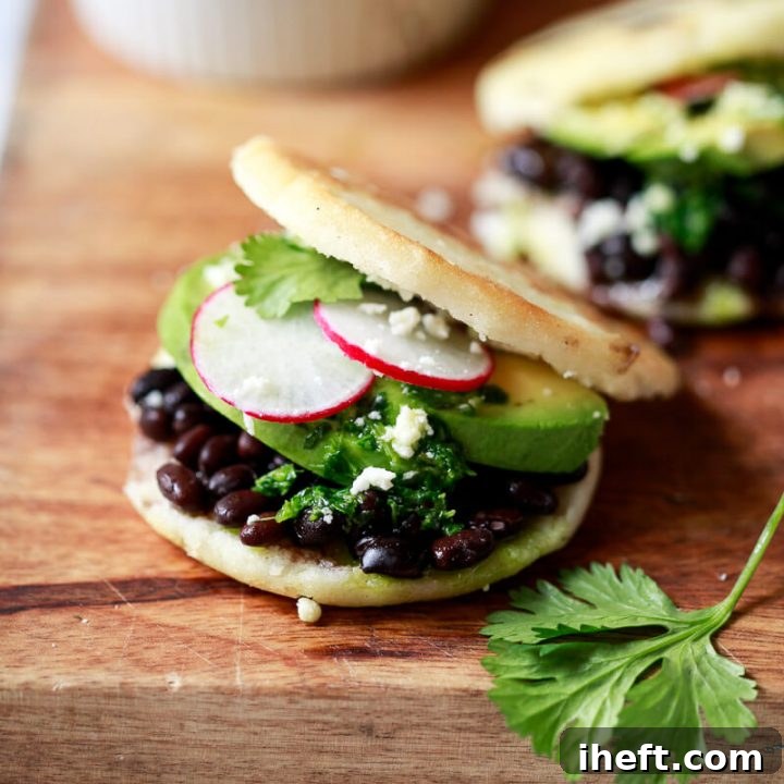 Close-up photo of an arepa filled with black beans, cheese, and avocado, ready to be enjoyed as a hearty meal.