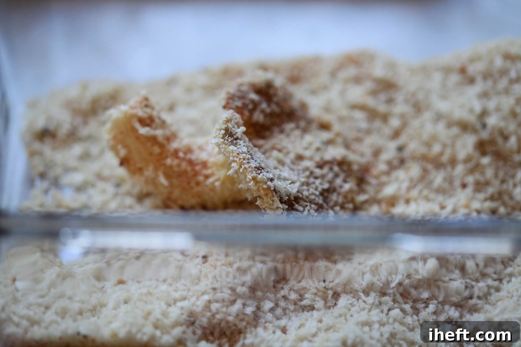 An oyster mushroom being coated in the seasoned breadcrumb mixture, ensuring even coverage for frying.