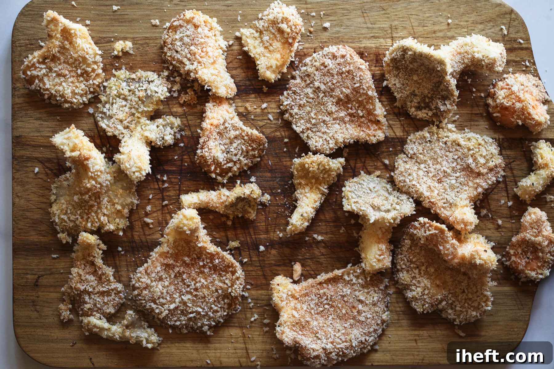 A plate of several oyster mushrooms, uniformly coated in breadcrumbs and spices, ready for frying.