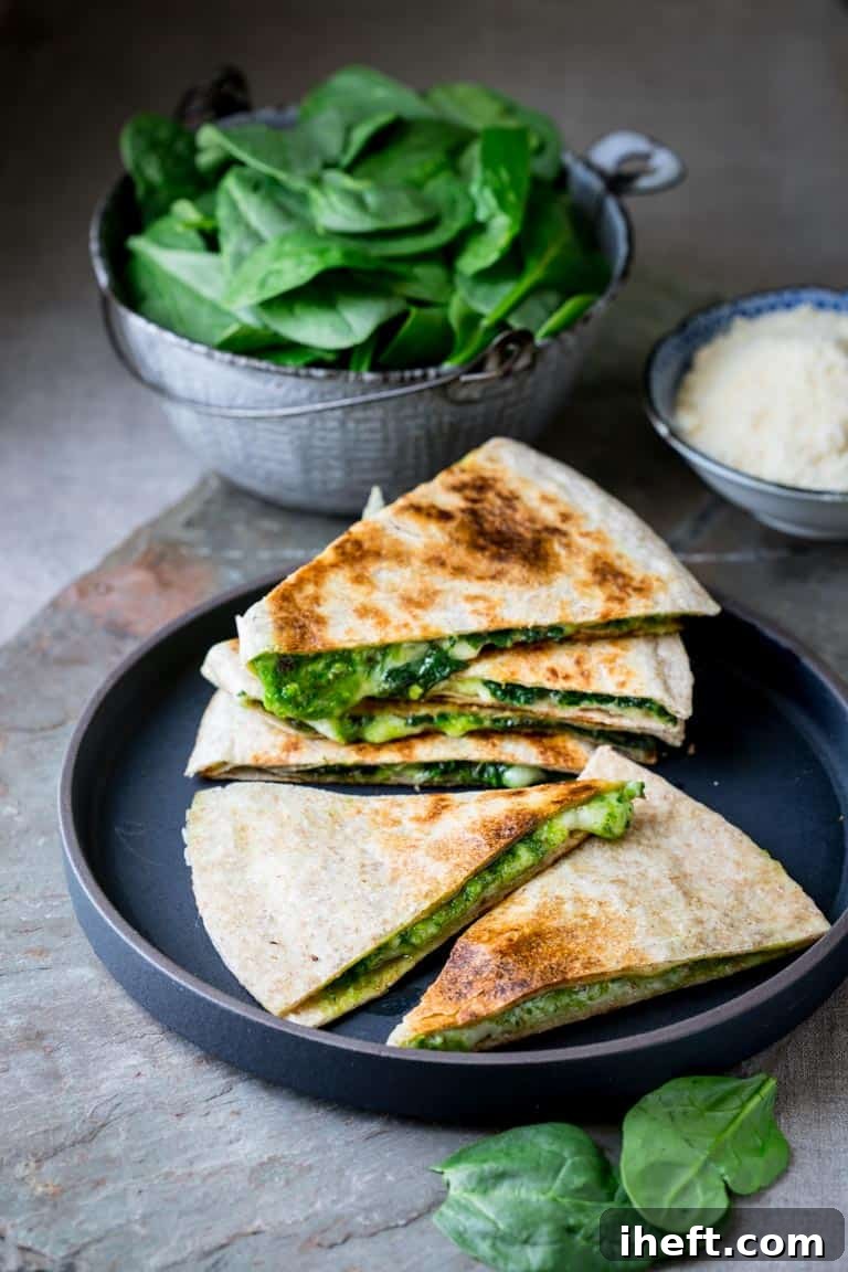 Delicious vegetarian spinach pesto and cheddar quesadillas served on a dark grey plate, a perfect Blackstone griddle recipe.