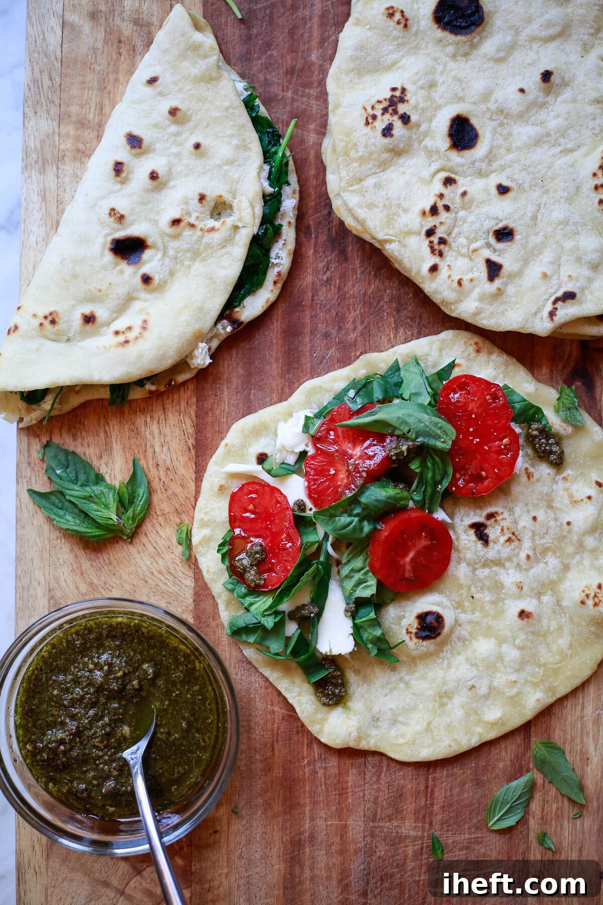 Grilled Piadina, an Italian flatbread, arranged on a cutting board and generously topped with fresh mozzarella, ripe tomatoes, and fragrant pesto.