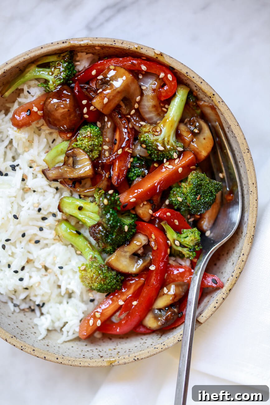 An overhead view of vibrant, easy stir fry vegetables, expertly cooked on a griddle, served alongside fluffy white rice.