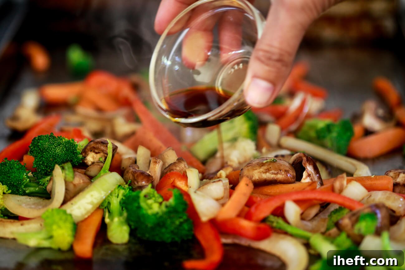 A hand expertly pours savory stir fry sauce over a medley of sizzling vegetables on a griddle, adding the final flavor.