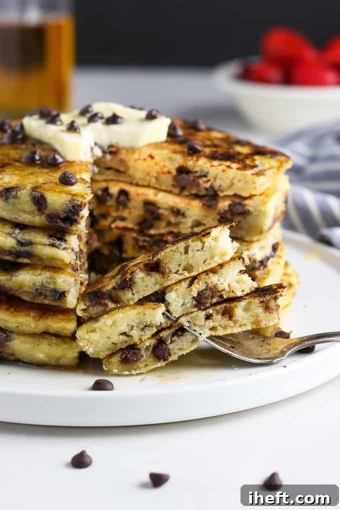 A perfectly stacked tower of fluffy Vegan Chocolate Chip Pancakes on a pristine white plate, promising a delightful breakfast.