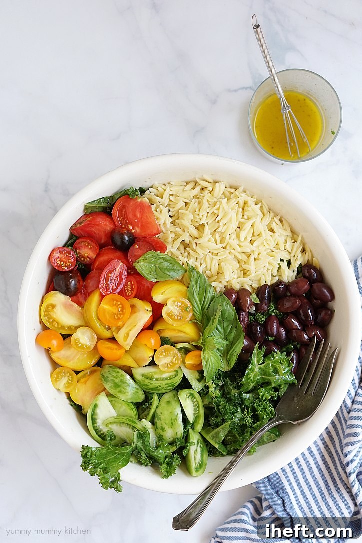 A beautifully presented vibrant vegan kale, heirloom tomato, and orzo salad in a large serving bowl, garnished with fresh basil leaves. Ideal for healthy meal preparation or impressing guests at a party.