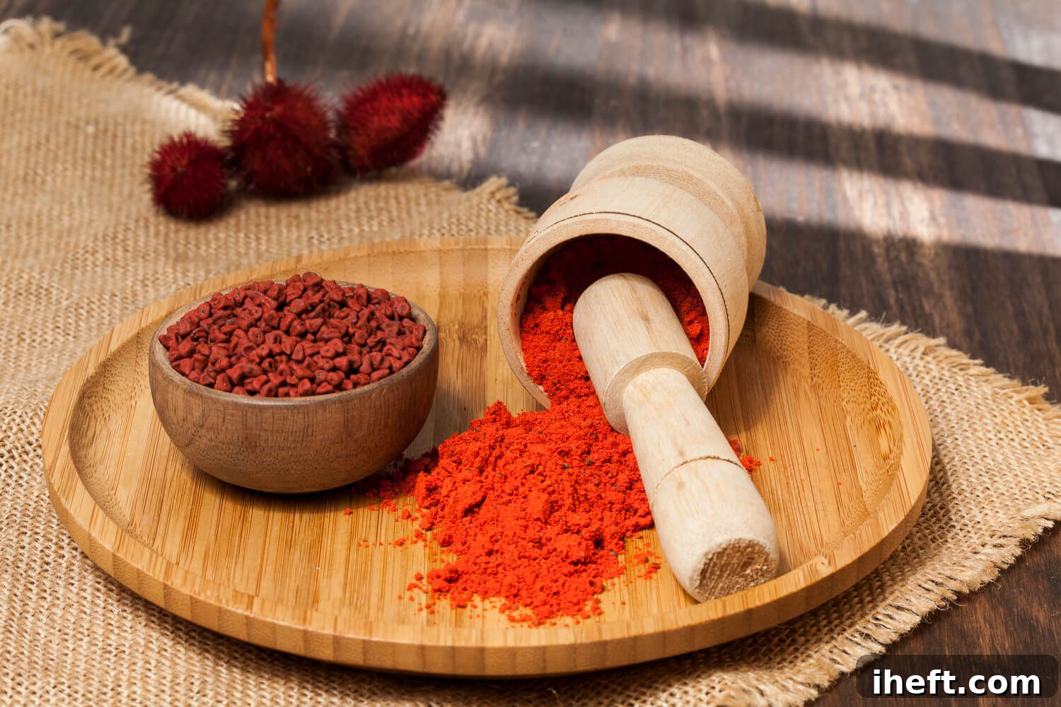 A bowl of achiote seeds sits next to a mortar and pestle filled with ground annatto. 