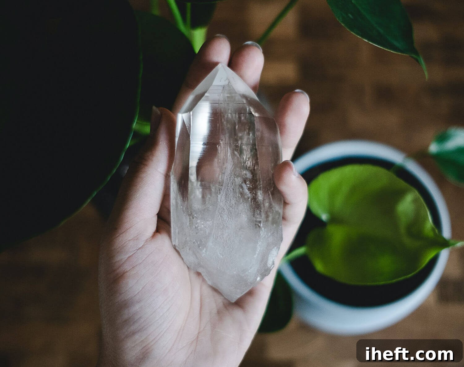 Close up photo of a hand holding a large clear crystal. 