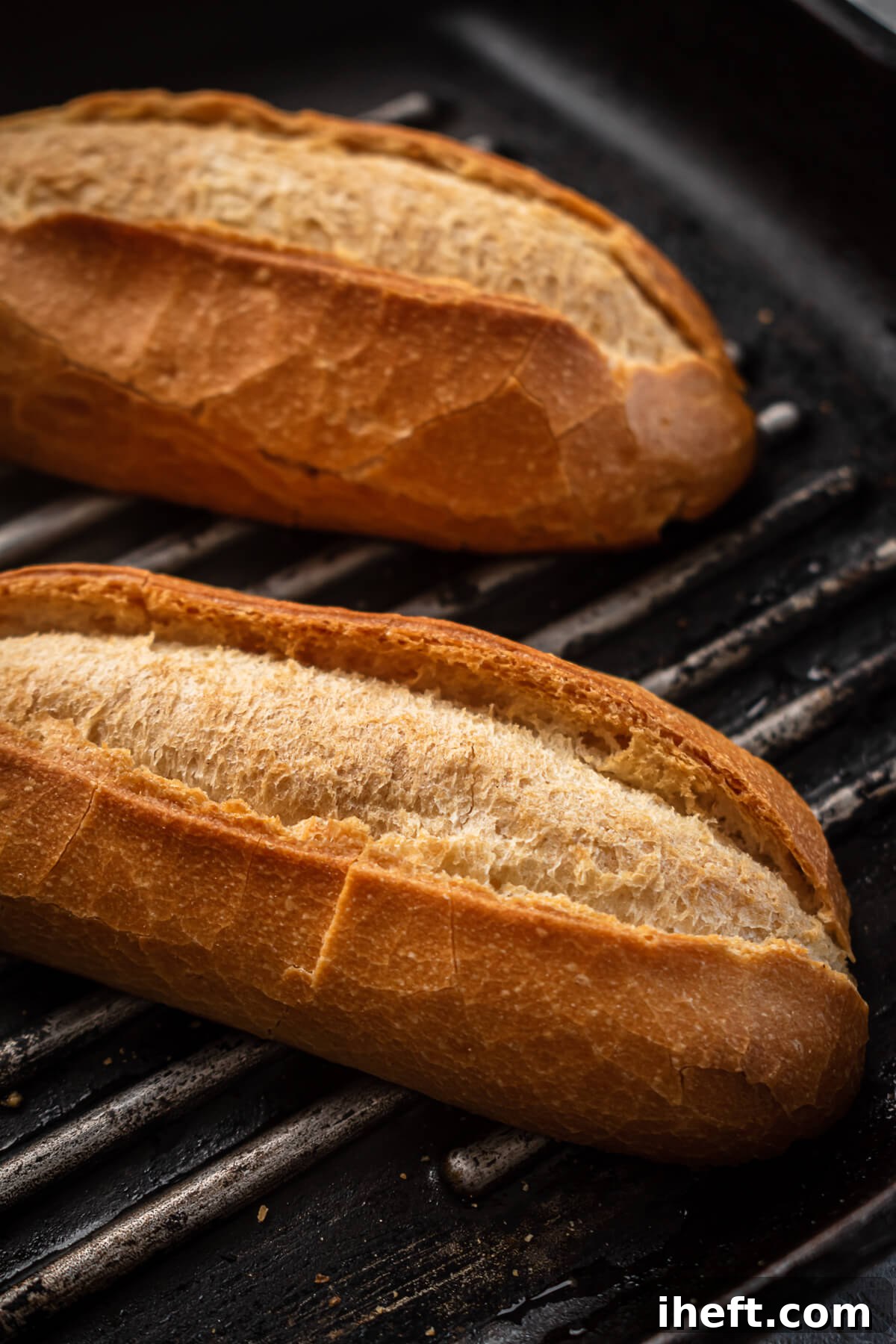 Baguette halves toast on a grill.
