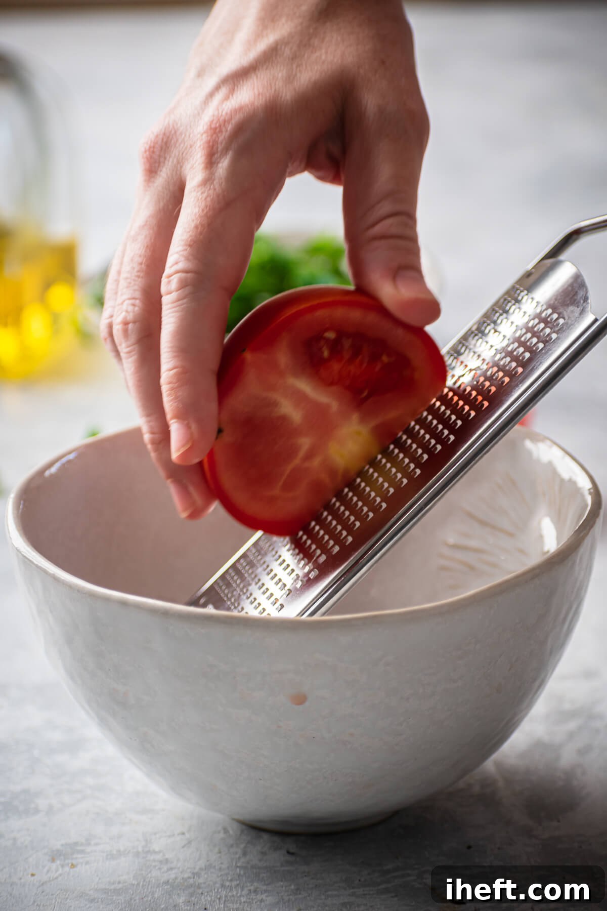 A tomato is grated into a bowl.