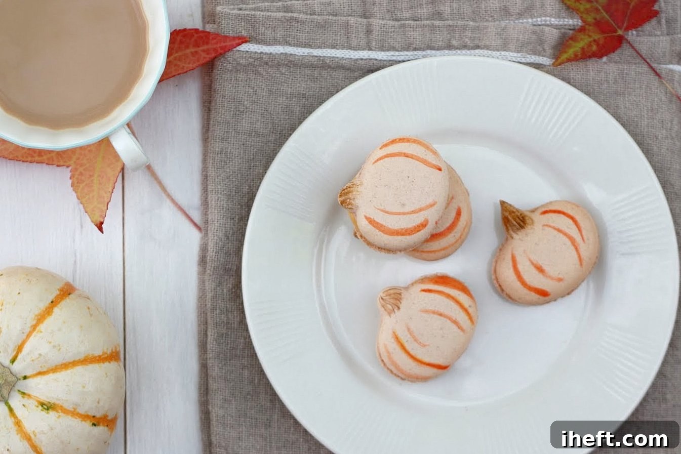 Pumpkin French Macarons on a plate with autumn leaves. These cookies are a delightful fall dessert.
