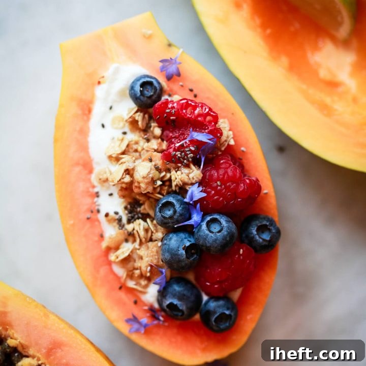 A vibrant overhead photo showcasing a beautifully prepared papaya boat, a papaya half with a lime wedge, and a papaya half with seeds, all arranged on a elegant marble surface.