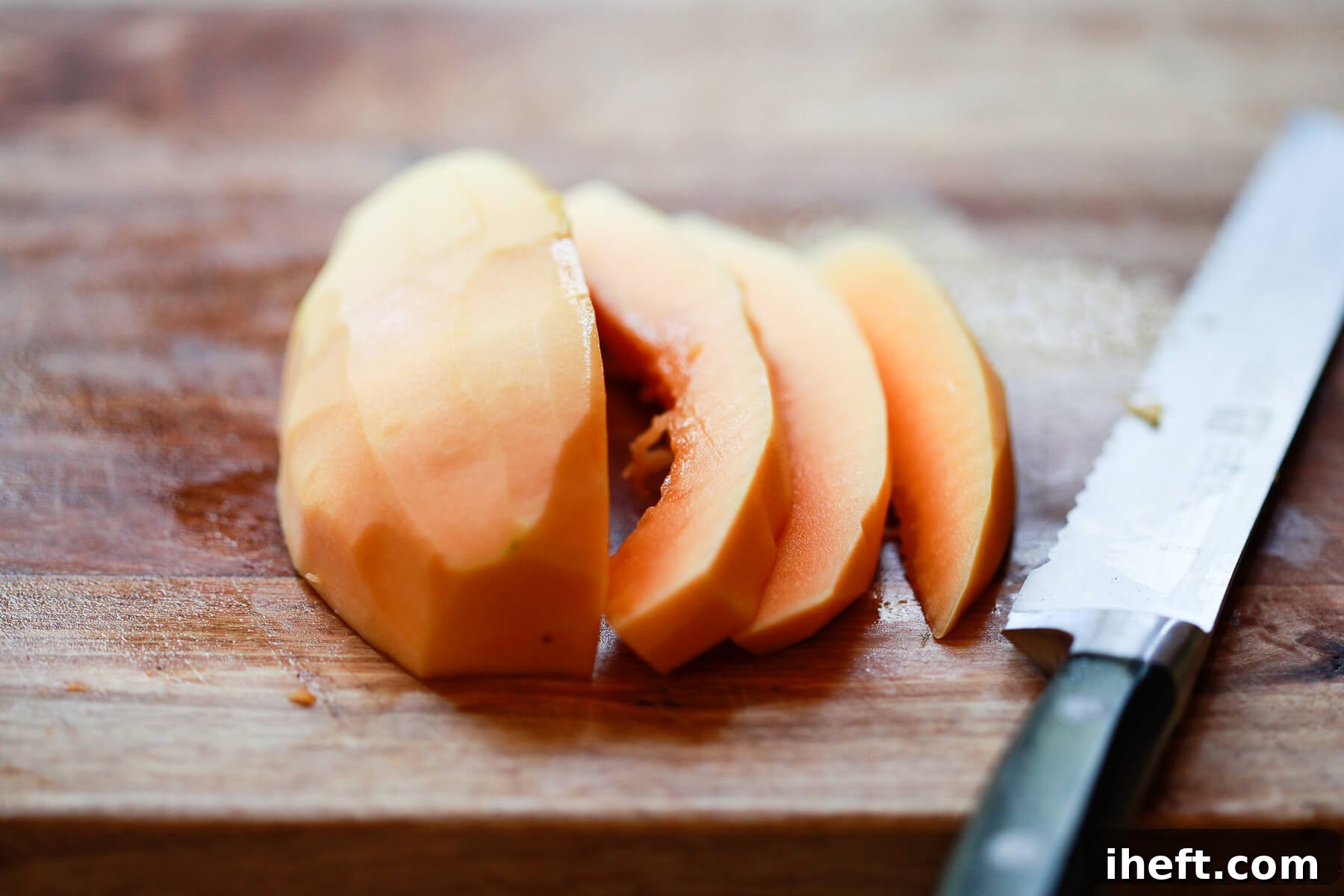 Perfectly peeled Hawaiian papaya has been expertly sliced and cubed, ready for serving on a wooden cutting board.