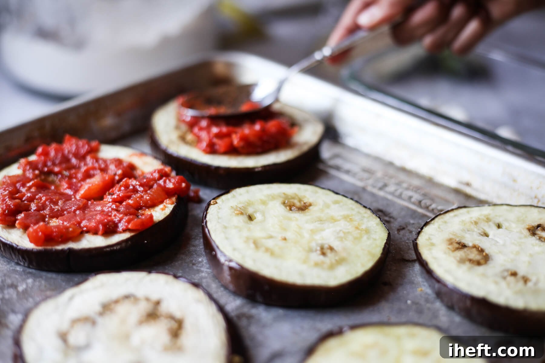Sauce is spooned over cooked eggplant rounds to make Julia Child's eggplant pizza bites.