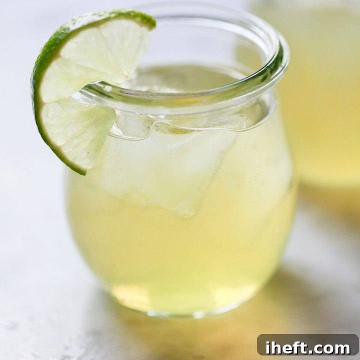 Close-up photo of a green tea shot in a small jar garnished with a lime slice.