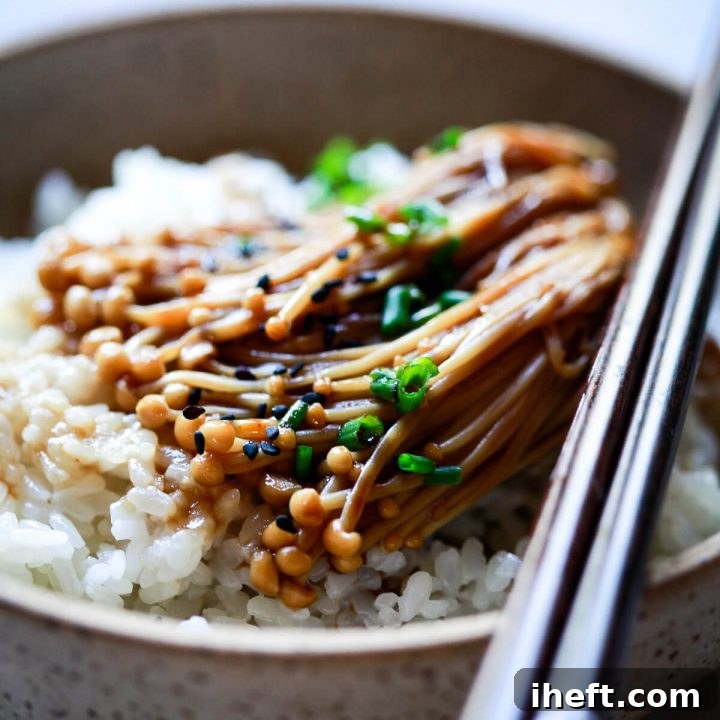 Enoki mushrooms with teriyaki and soy sauce served over rice and topped with chives and black sesame seeds.