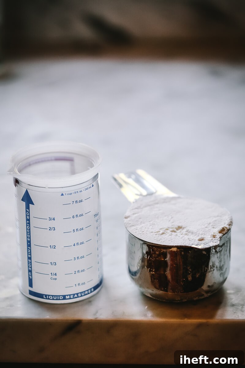 A measuring cup filled with flour, surrounded by measuring spoons, illustrating precise kitchen measurements.