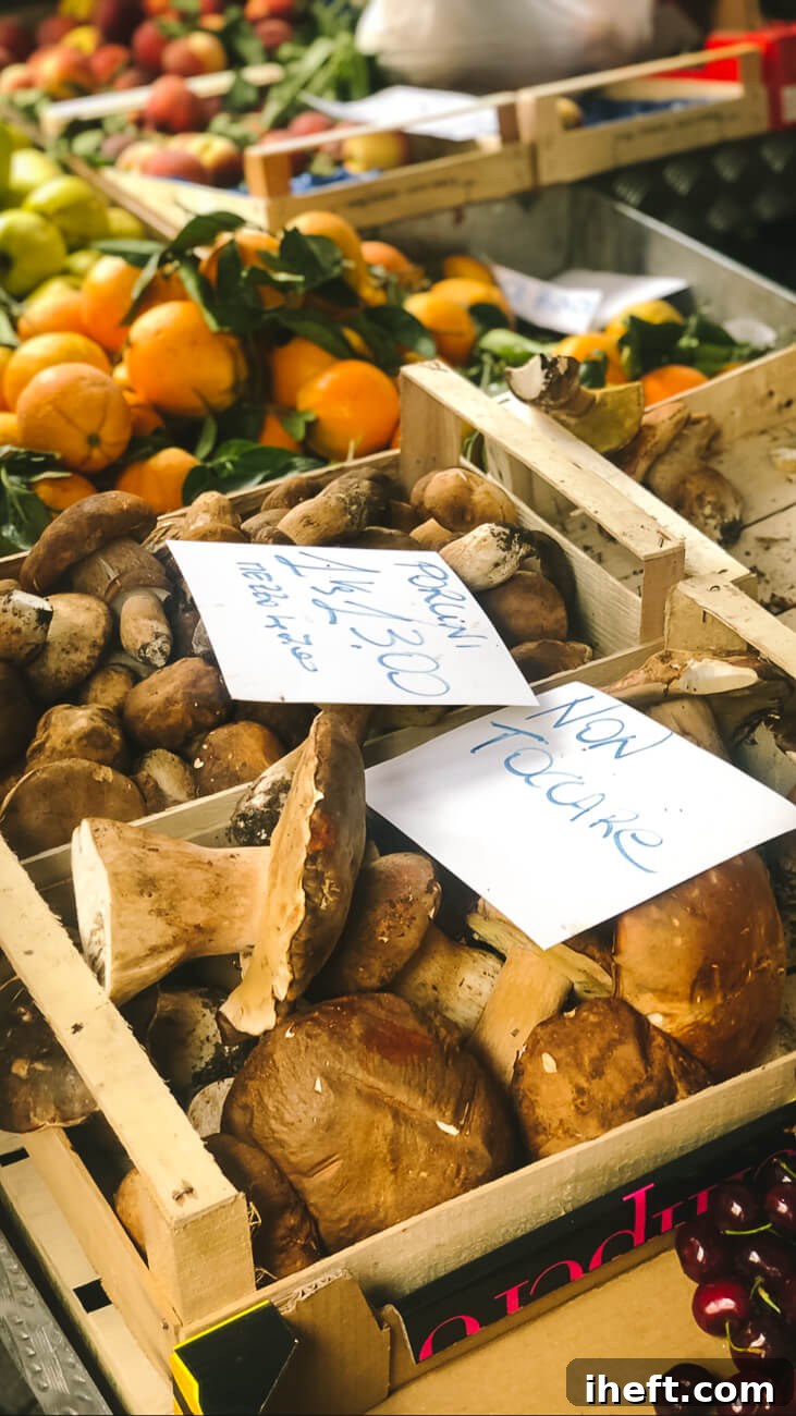 A beautiful display of fresh, earthy porcini mushrooms, likely harvested recently, at a vibrant farmers market in Tuscany.
