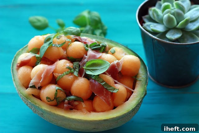 A vibrant melon and prosciutto salad featuring perfectly scooped cantaloupe balls and fresh basil leaves, ready to be served.