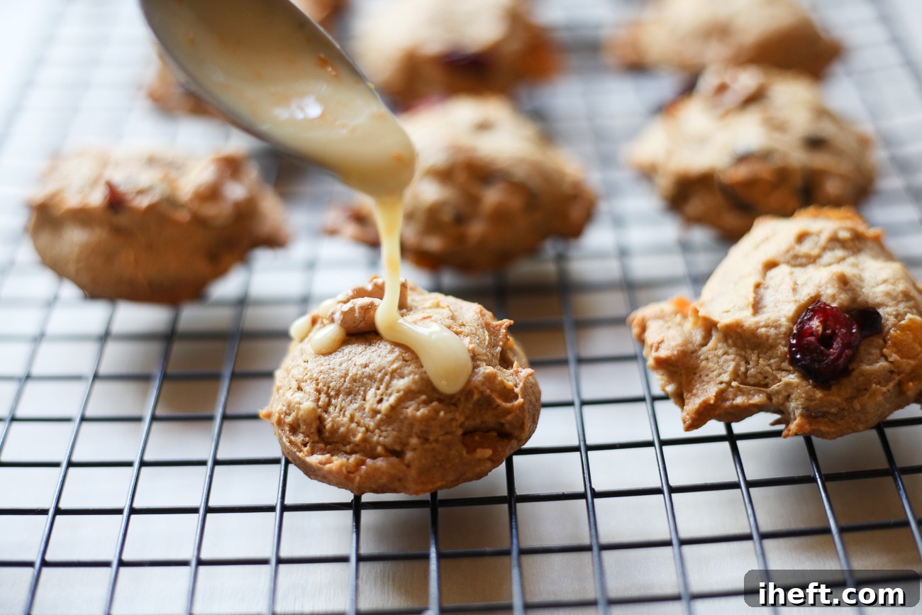Vibrant orange glaze being artfully drizzled over a batch of perfectly cooled persimmon cookies on a wire rack, adding a final touch of sweetness and citrus zest.