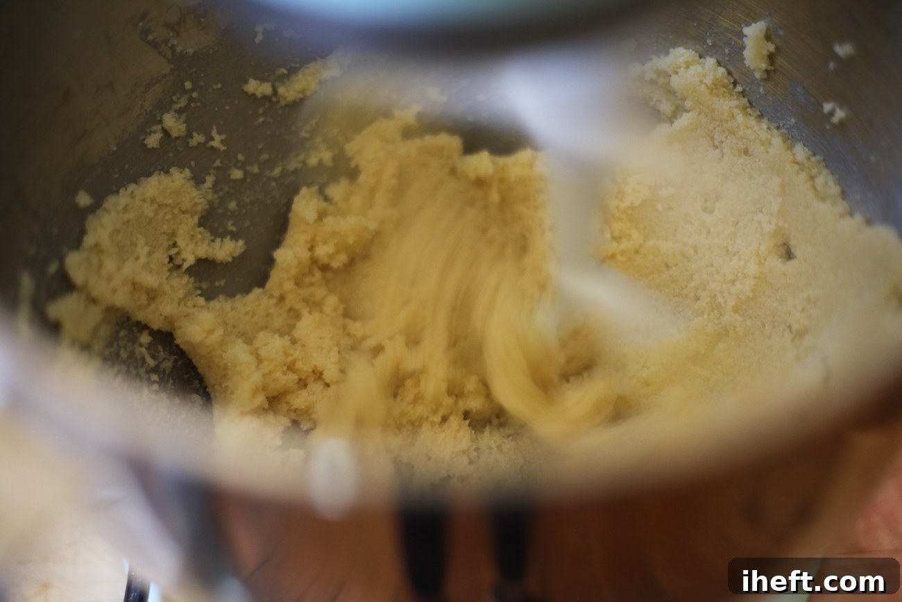 Butter and sugar being creamed together until light and fluffy in a KitchenAid stand mixer, demonstrating the first step of cookie dough preparation.