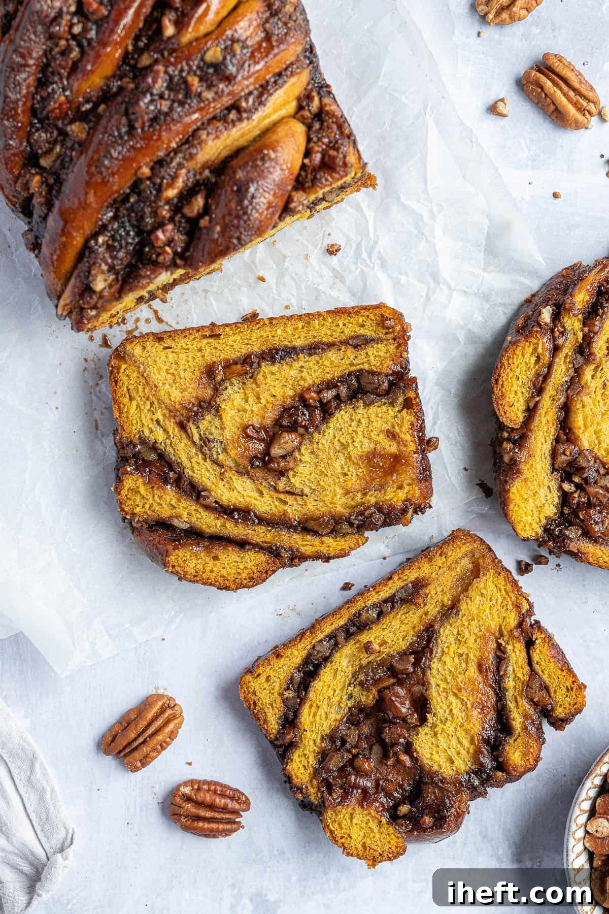 An over head photo of a pumpkin and pecan swirled babka loaf cut into slices. 