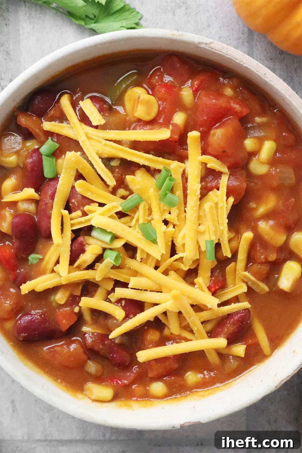 An overhead photo of a bowl of vegan chili topped with vegan cheddar cheese. 