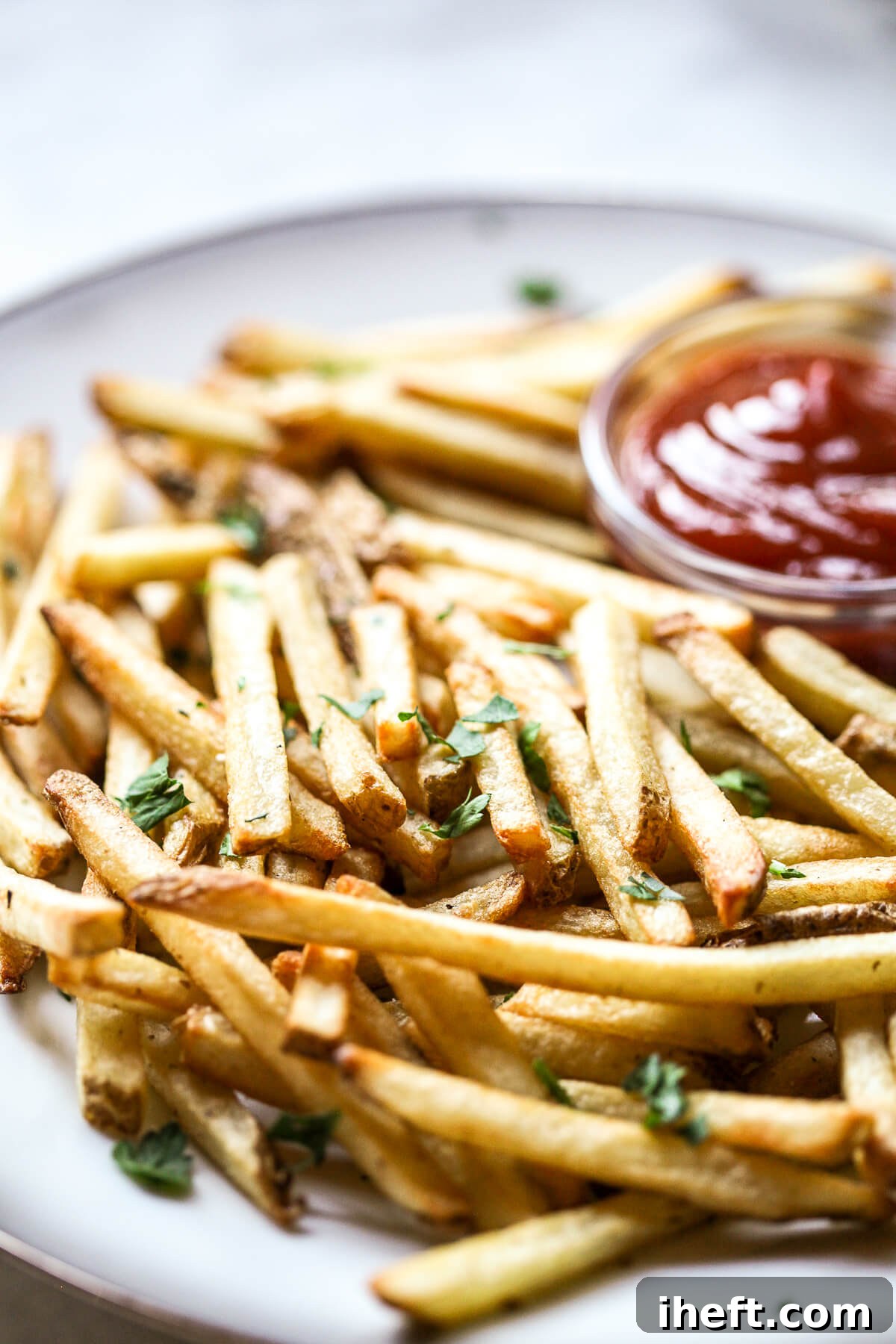 A plate brimming with golden-brown, crispy French fries cooked perfectly in an air fryer.