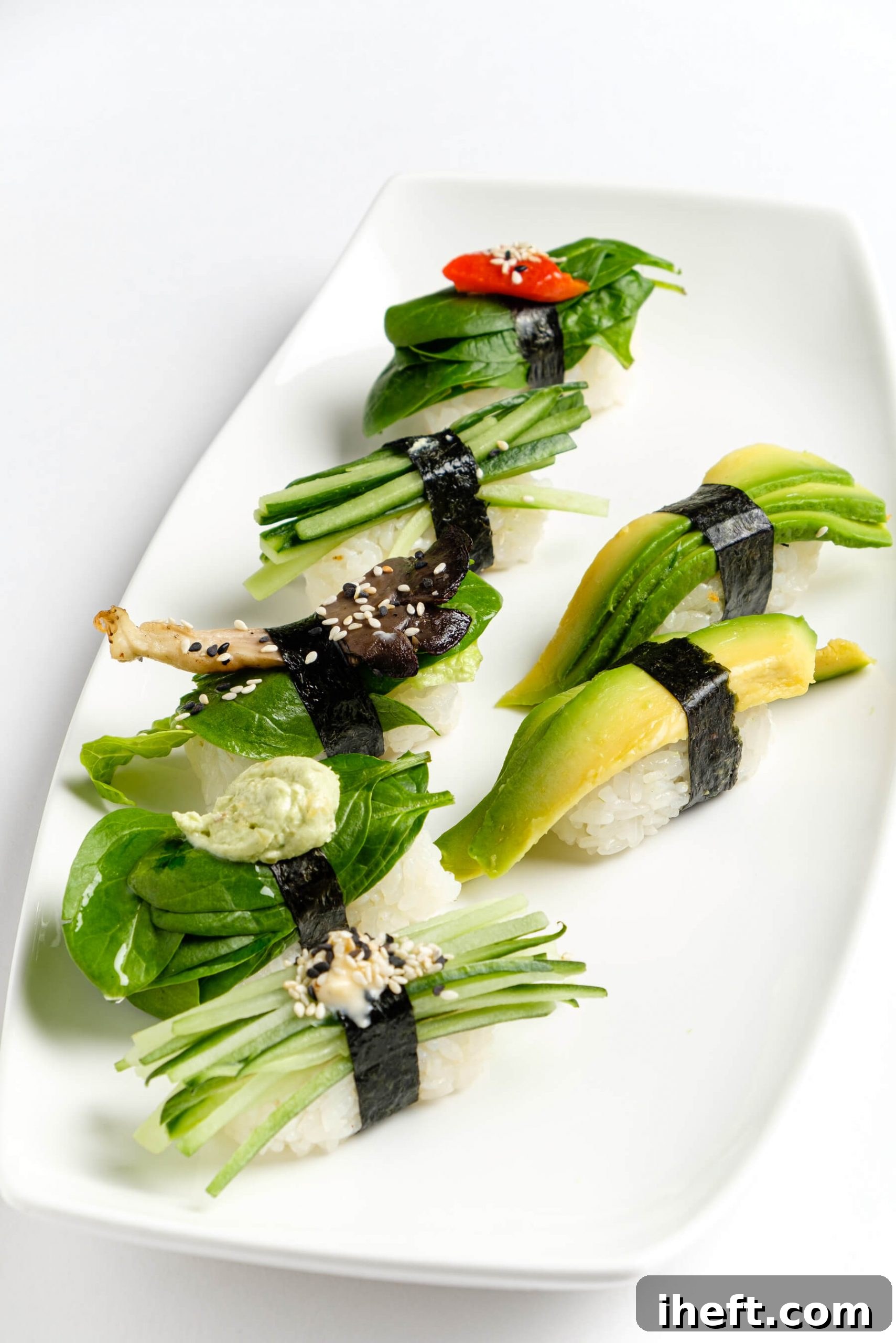 A crisp white platter showcasing an artful arrangement of vegan nigiri, featuring vibrant avocado, refreshing cucumber, and savory oyster mushrooms delicately placed over seasoned sushi rice.