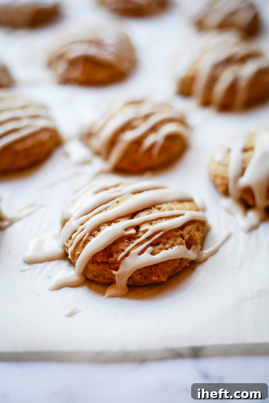 A close-up photo of vegan pumpkin cookies with vanilla icing drizzle, showcasing their soft texture and appealing appearance.