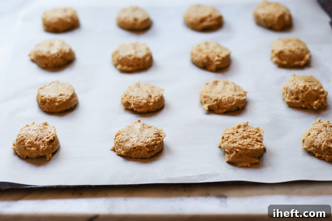 Vegan pumpkin cookie dough balls on a parchment lined cookie sheet ready for the oven.