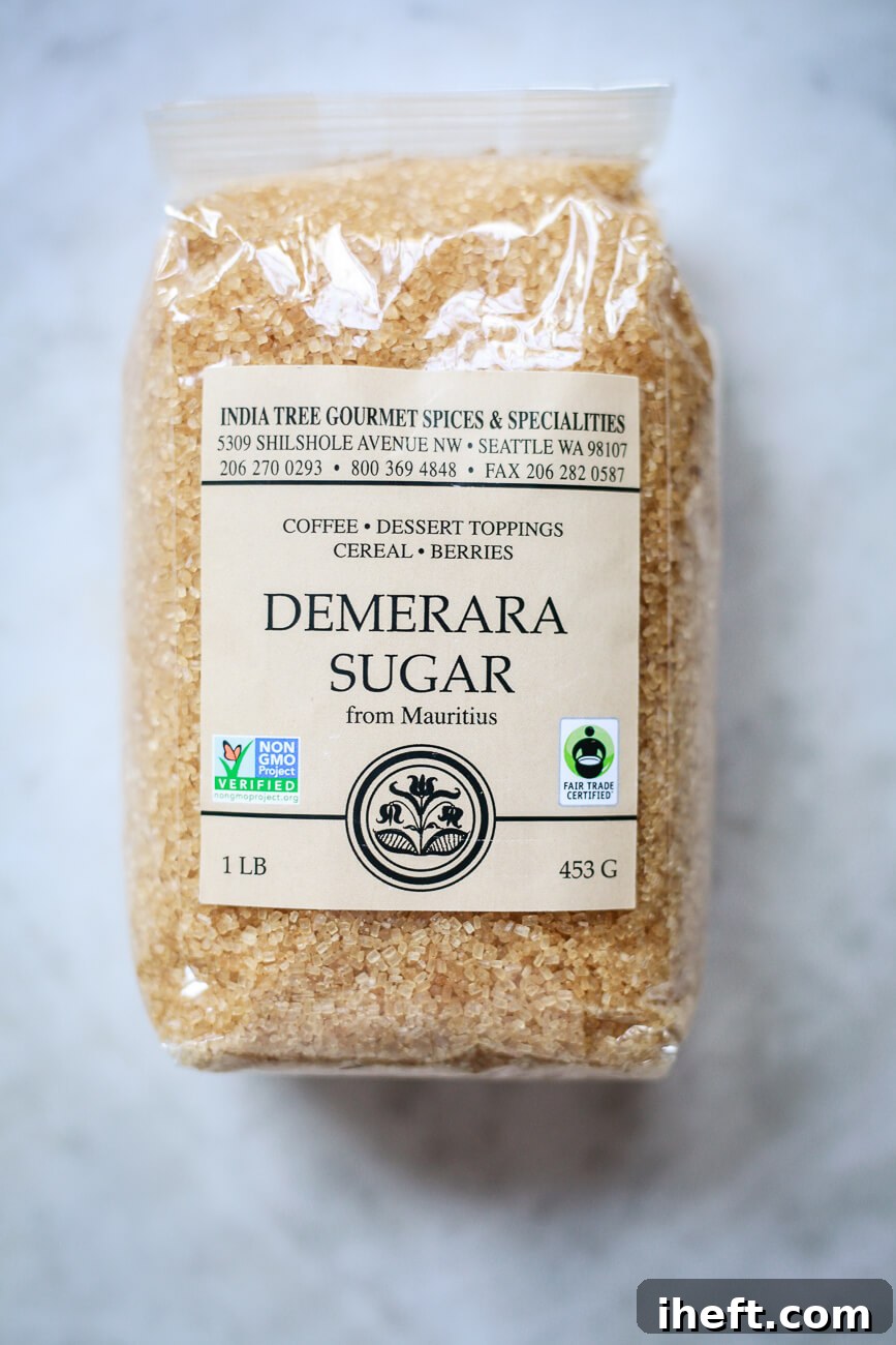 A package of demerara sugar with large golden colored sugar crystals sits on a marble surface. 