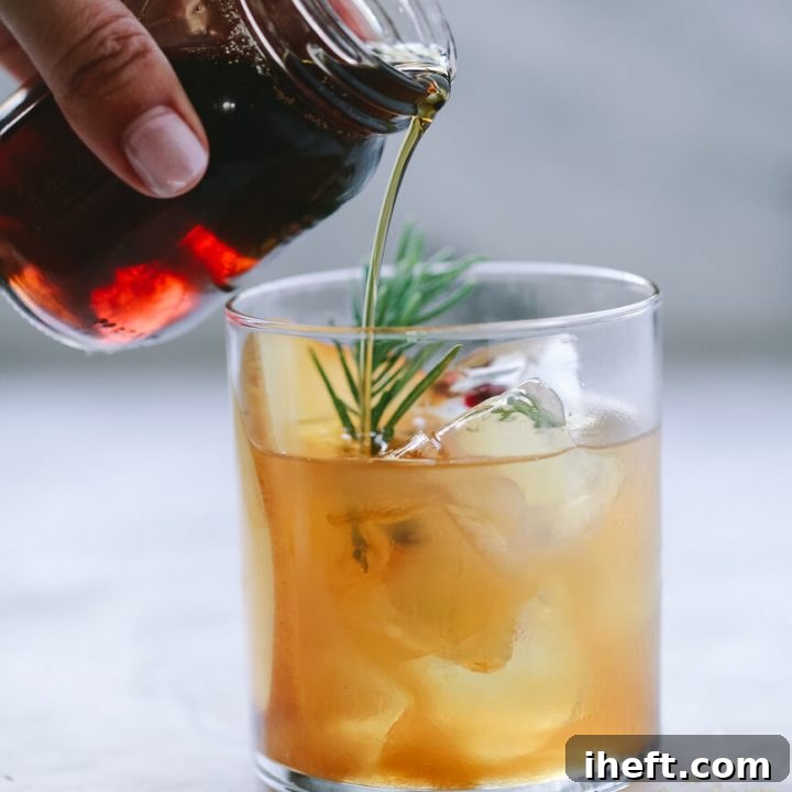 A small jar of homemade Demerara syrup is poured into an old fashioned bourbon cocktail.