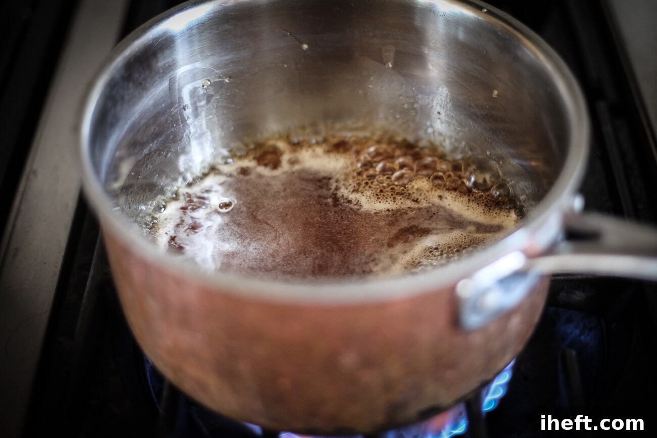 Demerara syrup simmers in a small copper saucepan on the stove.