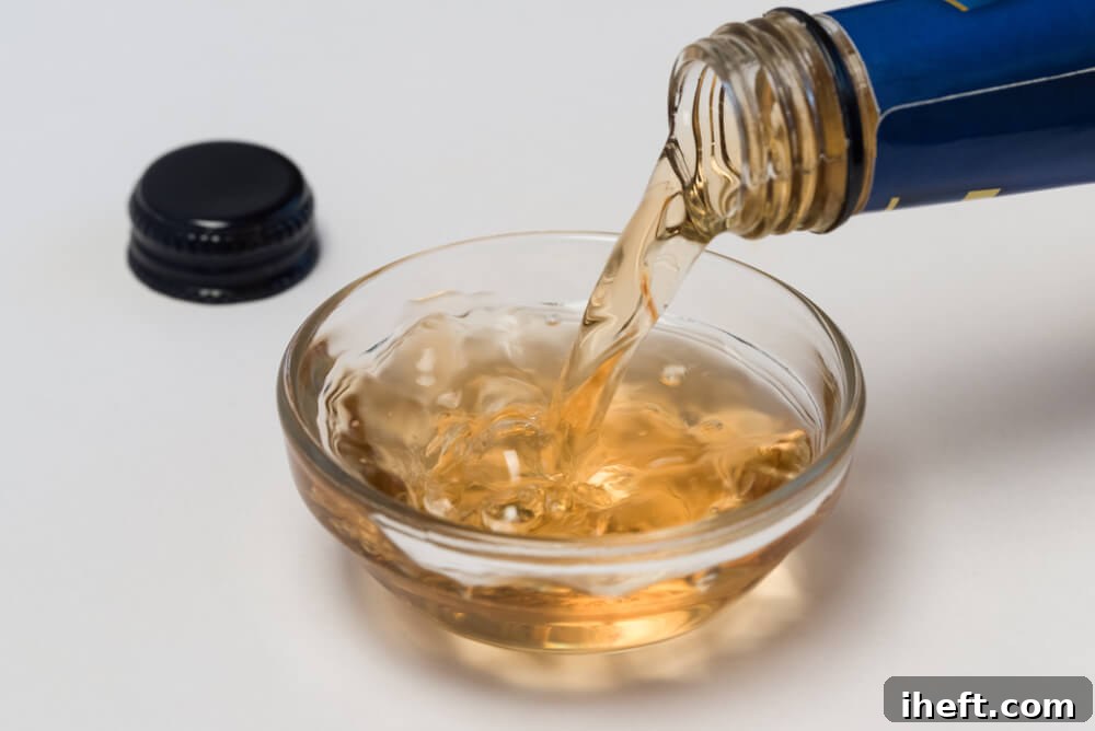 A stream of rich, amber-brown sherry vinegar is being poured into a small glass bowl, highlighting its distinctive color and suggesting its use as a refined culinary ingredient.