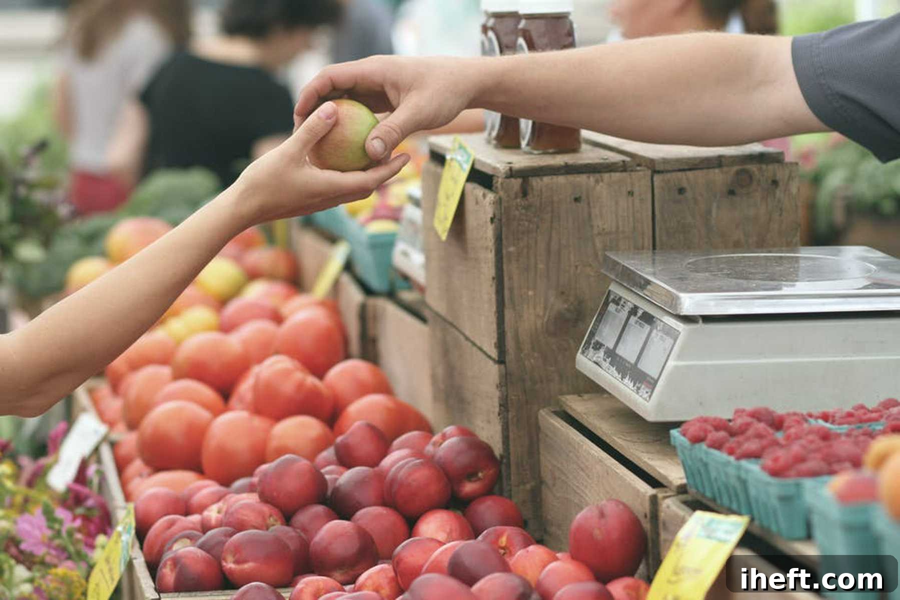 A child's hand reaches for a fresh, red apple from a seller's display at a vibrant farmer's market, symbolizing freshness and local produce.
