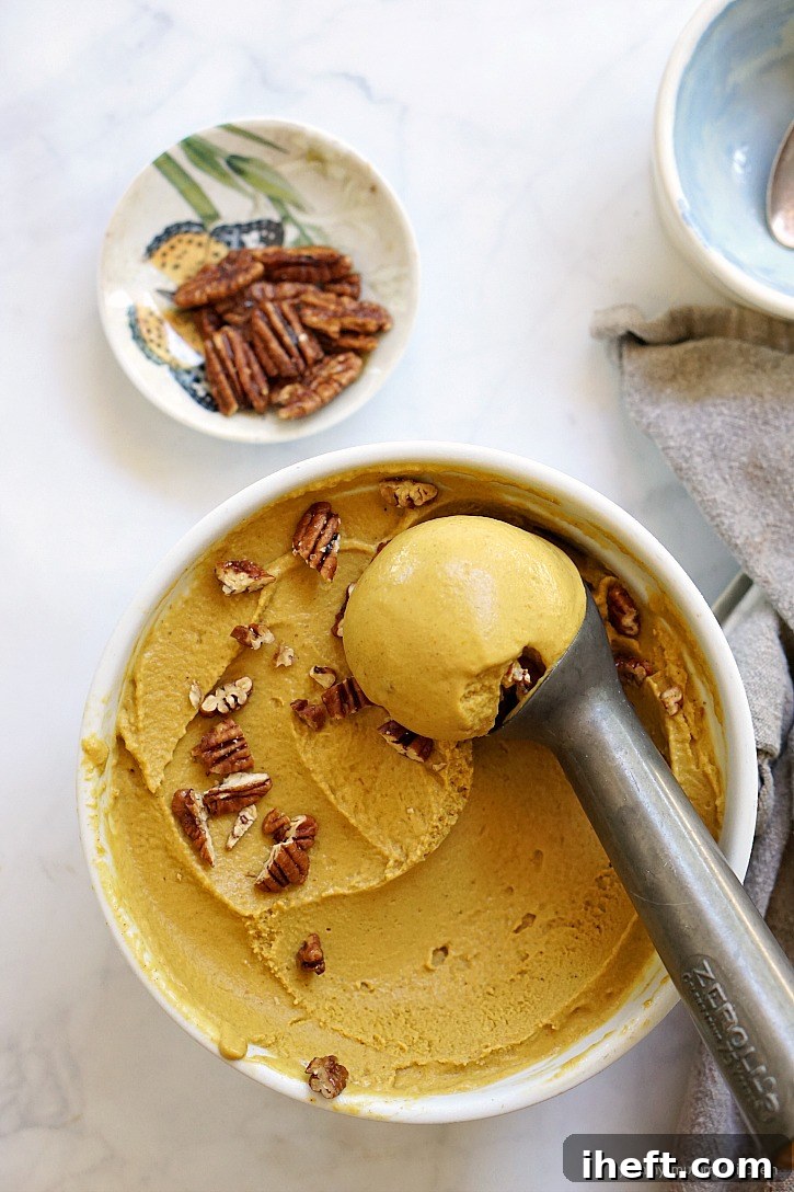 Deliciously creamy vegan pumpkin pie ice cream made with healthy ingredients like coconut milk and maple syrup, topped with crunchy pecans.