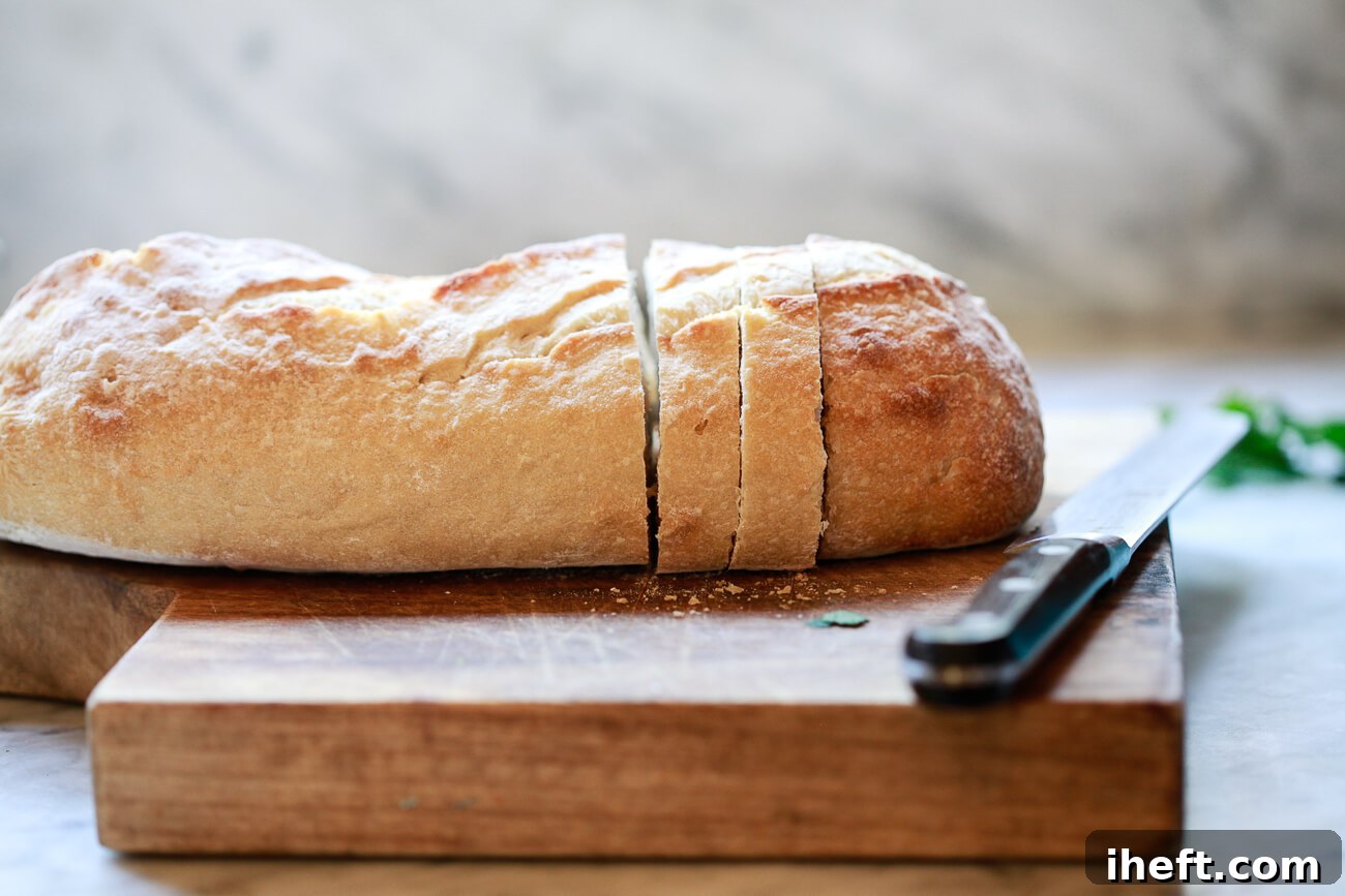 Sliced rustic sourdough on a cutting board in a white kitchen.