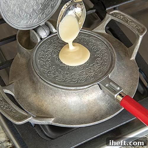A Nordic Ware Krumkake Iron sits on a gas stove, with batter being carefully poured onto the press, illustrating its traditional stovetop operation.