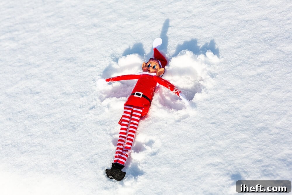 An elf on the shelf makes snow angels in the snow. 