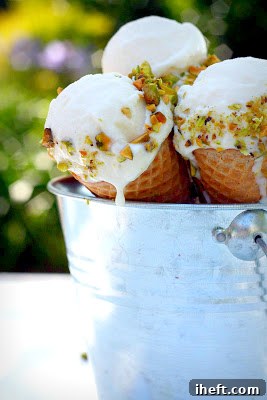 Two ice cream cones generously filled with homemade pistachio mascarpone gelato, with some melting and dripping, a perfect refreshing treat.
