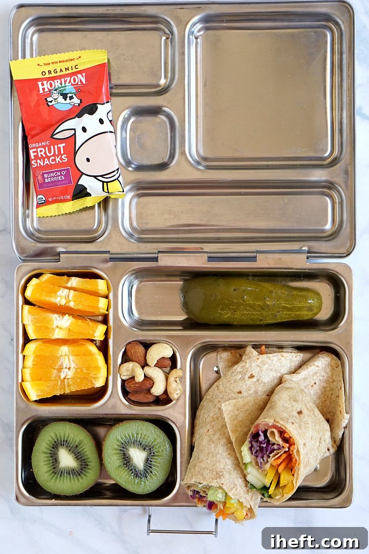A colorful lunch box packed with a rainbow veggie tortilla wrap, bursting with fresh produce.