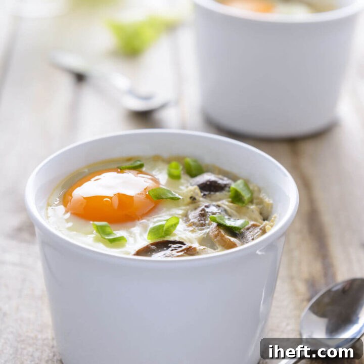 Two ramekins filled with Eggs en Cocotte. French baked eggs with cream.