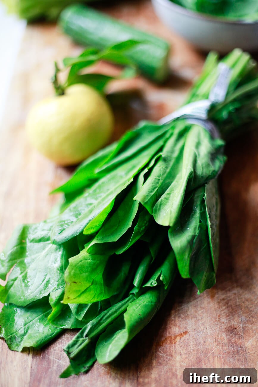 A vibrant bunch of dandelion greens rests on a rustic wooden cutting board, with a bright lemon partially visible in the soft background.